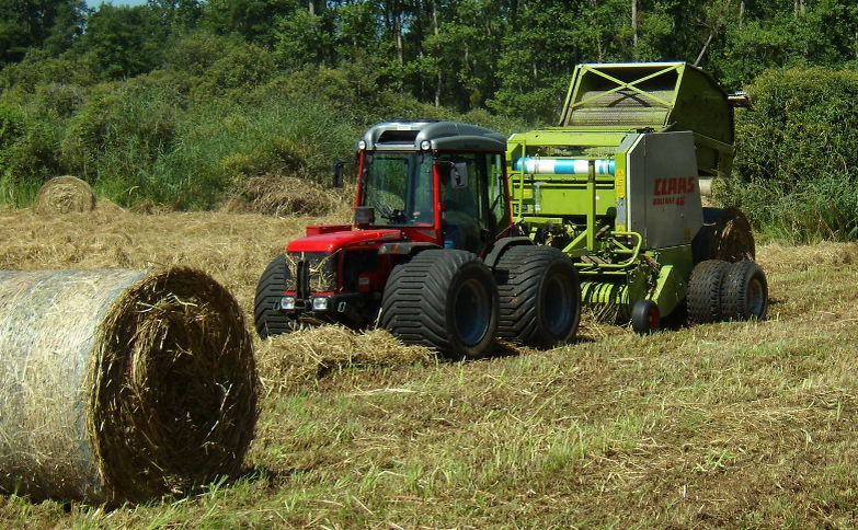 Fauche avec un tracteur à pneus extra larges basse pression et récolte de la matière à l’aide d’une presse à balle ronde montée sur boggie